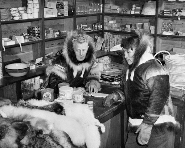 Leo Manning, manager at the Hudson's Bay Company trading post, lists the items exchanged for furs. Coppermine, N.W.T., [Kugluktuk (formerly Coppermine), Nunavut], 1949.  Richard Harrington / Canada. Dept. of Indian and Northern Affairs / Library and Archives Canada / PA-143236 