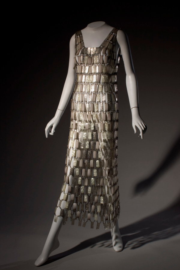Ankle-length, sleeveless, shift-silhouette wedding dress made of white, pearlescent, and silver glitter plastic rectangles attached with metal loops in “chainmail” style.