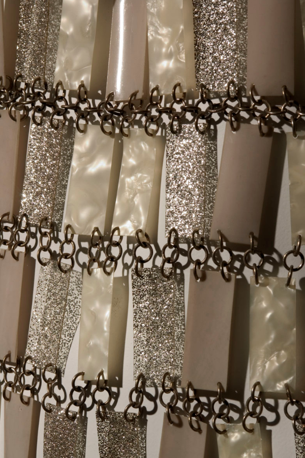 Ankle-length, sleeveless, shift-silhouette wedding dress made of white, pearlescent, and silver glitter plastic rectangles attached with metal loops in “chainmail” style.