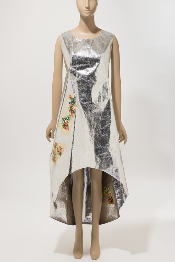 Metallic silver Mylar tent-silhouette dress with high-low hem. Dress has applied paper flower and butterfly motifs along the wearer’s right side and another at the back inside hem.