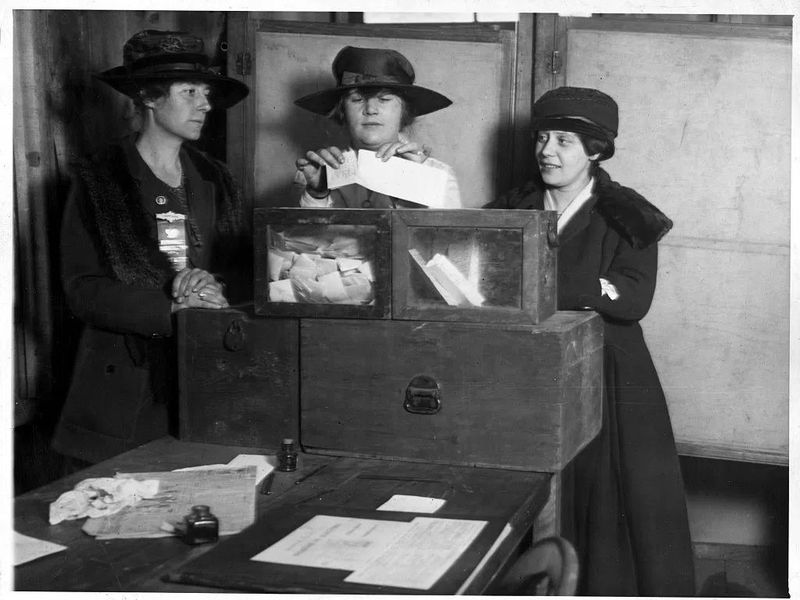 Two women cast their ballots in Wyoming while one looks on, August 26, 1920