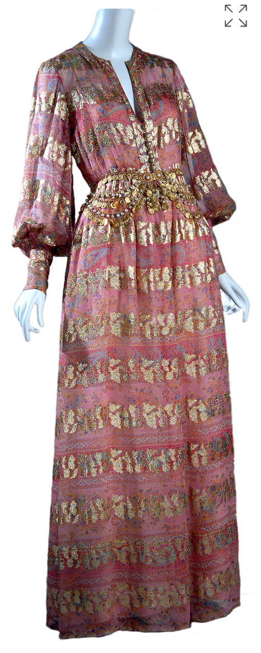 Front view of the 1968 Christian Dior for Bonwit Teller longsleeve floor length pink evening dress with gold-brocaded paisley bands evenly spaced throughout the fabric. A layered coin and pearl belt is worn at the waist.